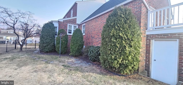 view of property exterior featuring fence and brick siding