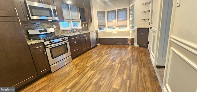 kitchen with dark wood-style floors, a sink, decorative backsplash, dark brown cabinetry, and appliances with stainless steel finishes