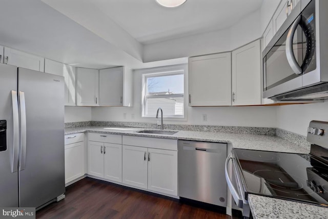 kitchen featuring appliances with stainless steel finishes, dark wood-style flooring, a sink, and white cabinets