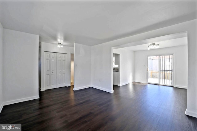 unfurnished living room with baseboards and dark wood finished floors