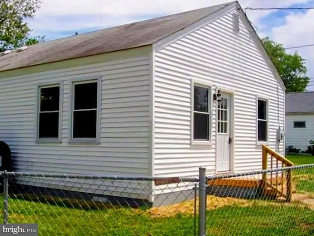 view of side of home featuring fence and a yard