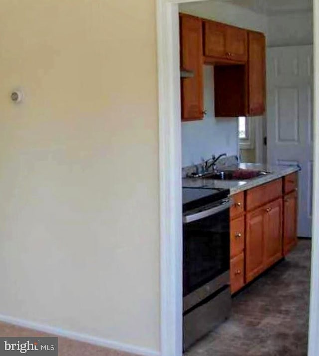 kitchen with electric stove, brown cabinets, light countertops, a sink, and baseboards