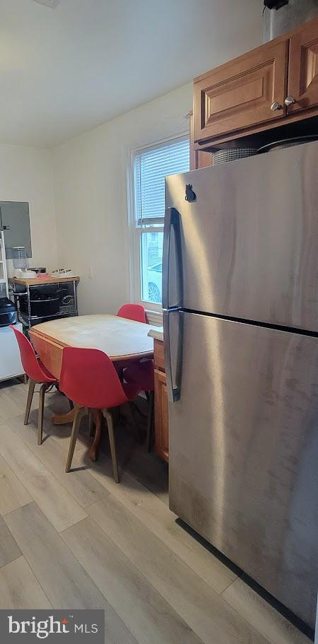 kitchen featuring freestanding refrigerator, light wood-style flooring, and brown cabinets