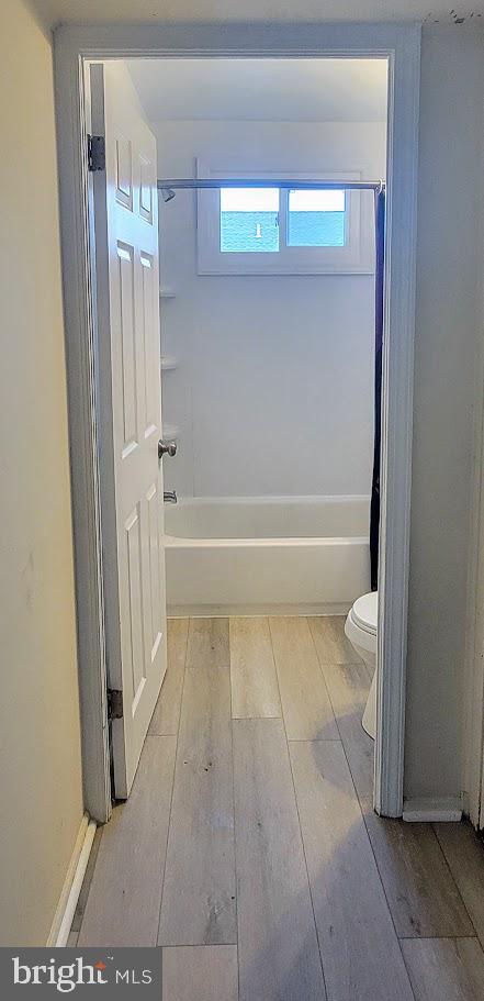 full bath with hardwood / wood-style flooring, toilet, and tub / shower combination