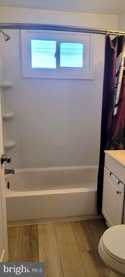 bathroom with wood finished floors, shower / bath combo with shower curtain, and plenty of natural light