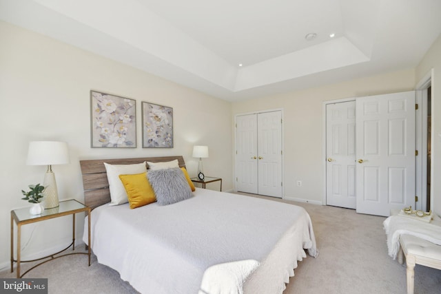 bedroom with a tray ceiling, carpet flooring, and baseboards