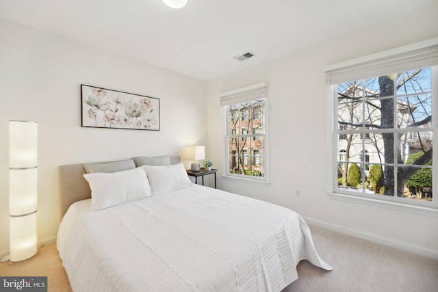 bedroom featuring multiple windows, baseboards, visible vents, and light carpet