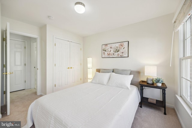 bedroom with multiple windows, baseboards, a closet, and light carpet