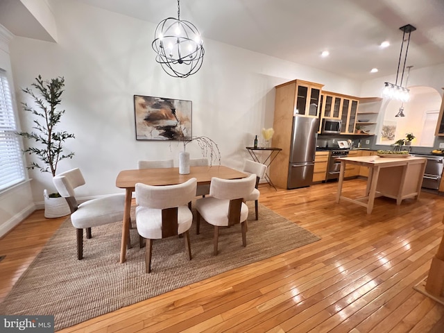 dining space featuring recessed lighting, light wood-type flooring, arched walkways, and a notable chandelier