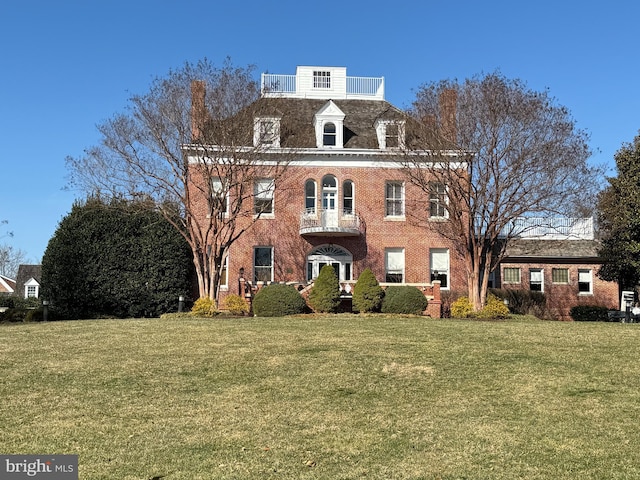 view of front of house featuring brick siding, a front lawn, and a balcony