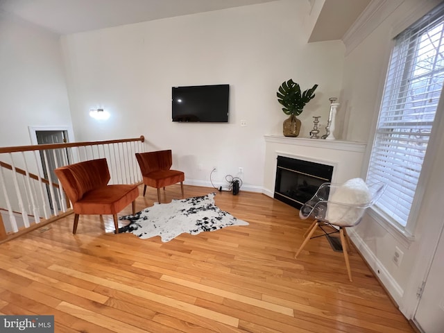 sitting room with a glass covered fireplace, hardwood / wood-style flooring, and baseboards