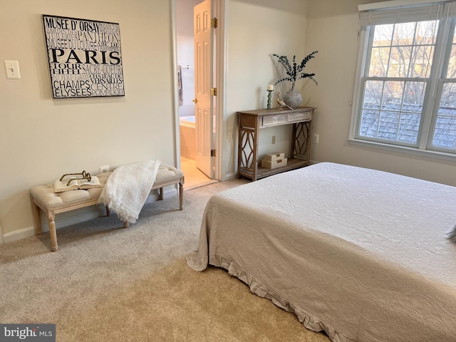 bedroom with ensuite bath, carpet, and baseboards