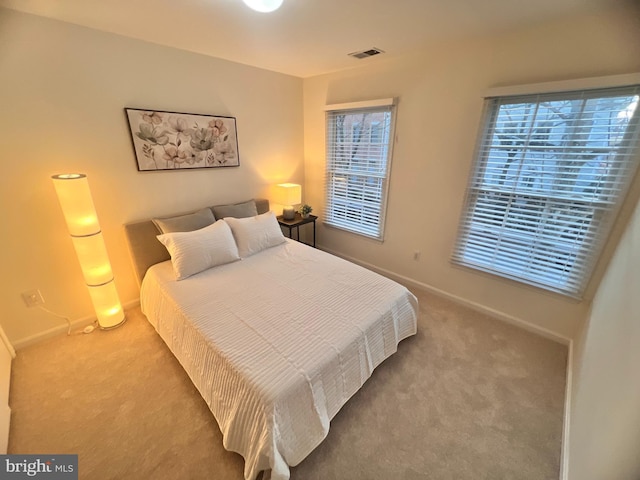 carpeted bedroom featuring multiple windows, baseboards, and visible vents