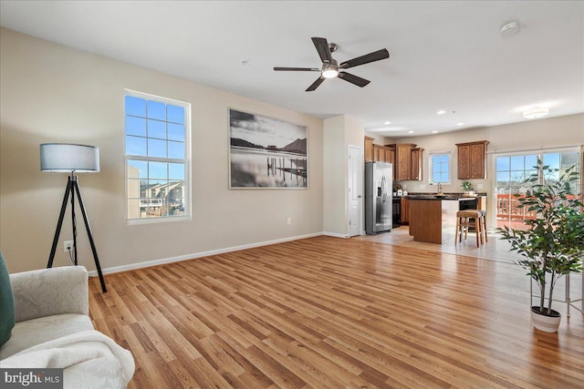 living area with light wood finished floors, recessed lighting, a ceiling fan, and baseboards