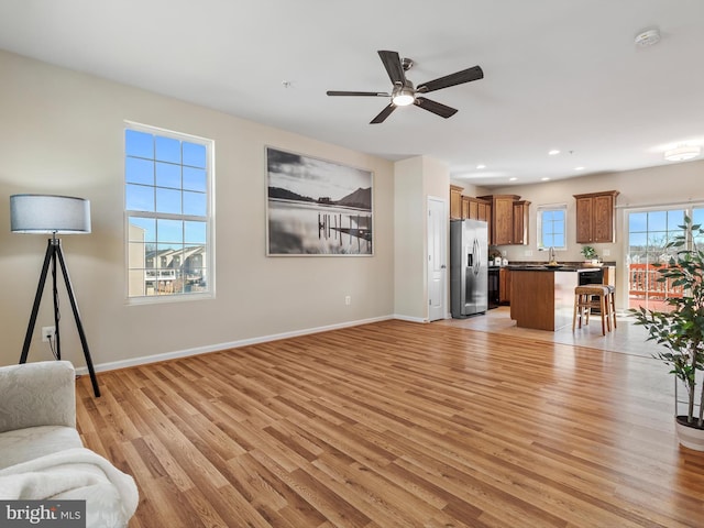 living area featuring recessed lighting, light wood-style flooring, a ceiling fan, and baseboards