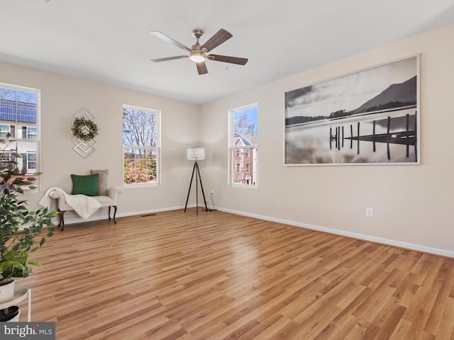 sitting room with baseboards, a ceiling fan, and light wood finished floors