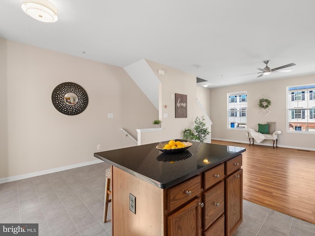 kitchen with a kitchen island, dark countertops, open floor plan, a breakfast bar area, and light tile patterned floors