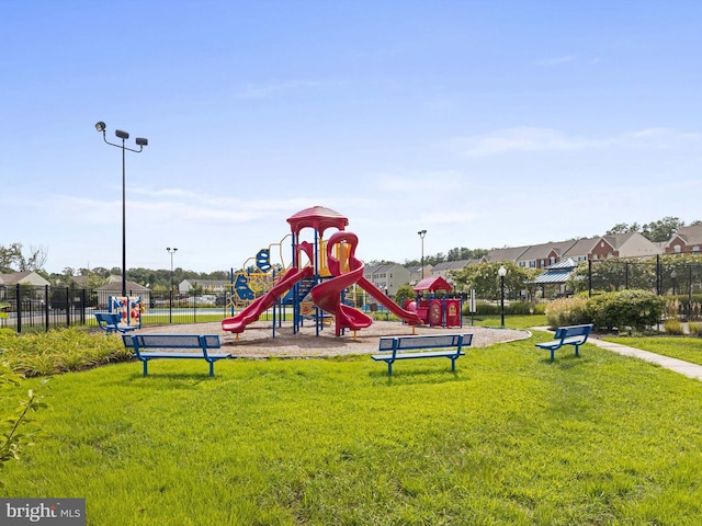 community jungle gym featuring a lawn and fence