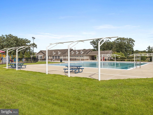 community pool with playground community, a yard, and fence