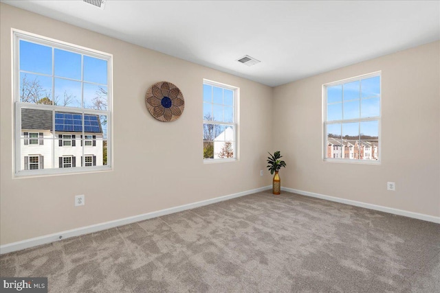 empty room featuring carpet, visible vents, and baseboards