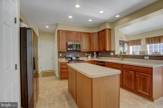 kitchen with tasteful backsplash, a kitchen island, light countertops, appliances with stainless steel finishes, and a sink