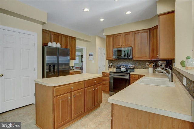 kitchen with a sink, backsplash, appliances with stainless steel finishes, and light countertops