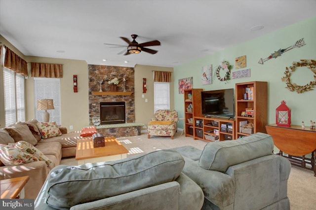 living room featuring light colored carpet, ceiling fan, and a fireplace