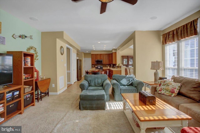 living area featuring visible vents, baseboards, light colored carpet, and ceiling fan