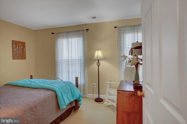 carpeted bedroom featuring visible vents, multiple windows, and baseboards