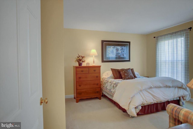 bedroom featuring light carpet and baseboards