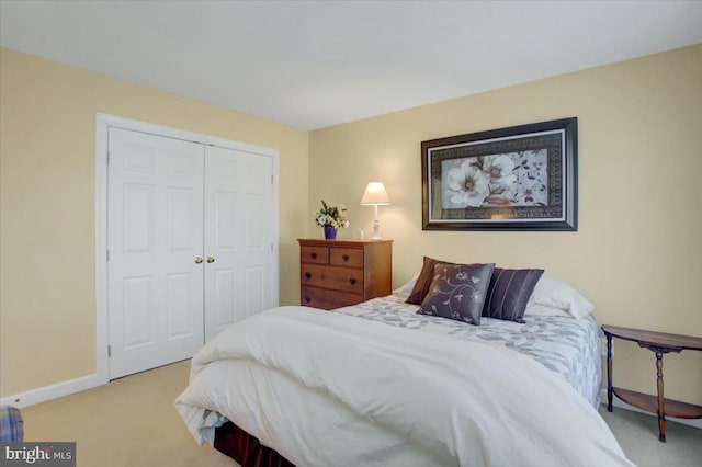 carpeted bedroom featuring baseboards and a closet