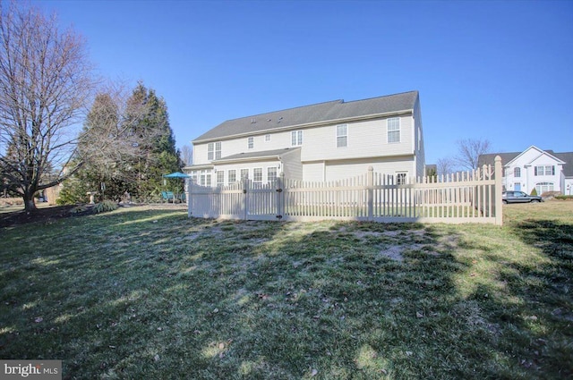 rear view of house featuring a lawn and fence