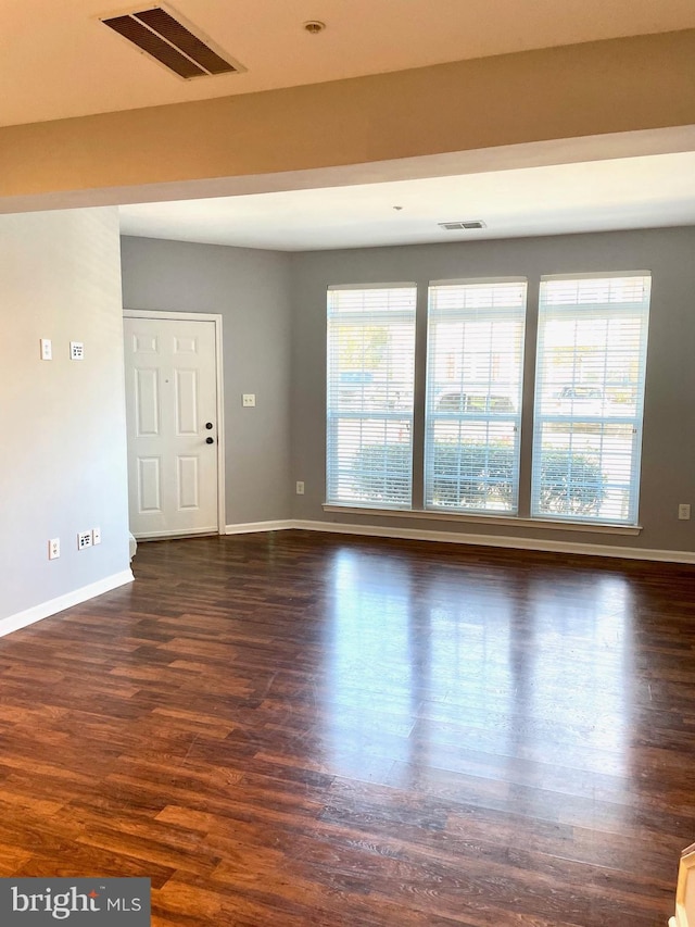 interior space with baseboards, visible vents, and dark wood-style flooring