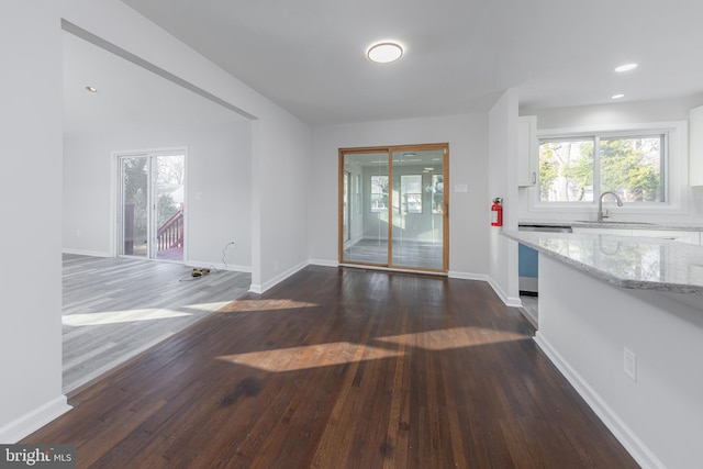 unfurnished dining area featuring recessed lighting, baseboards, dark wood-style flooring, and a sink