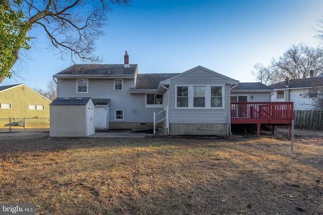 rear view of property featuring fence, a wooden deck, a chimney, a storage shed, and an outdoor structure