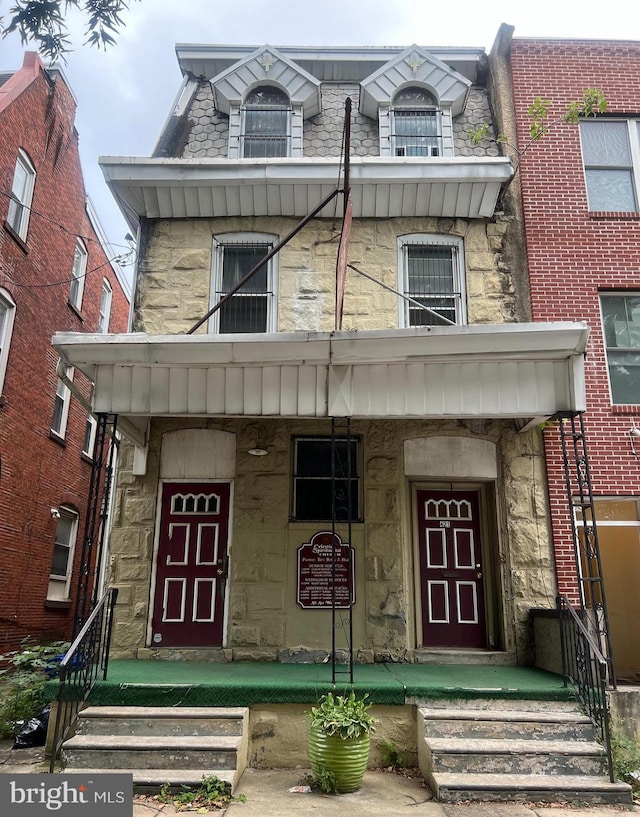 view of front of house with stone siding and a balcony