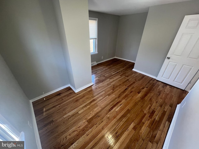 spare room featuring visible vents, baseboards, and dark wood-style flooring