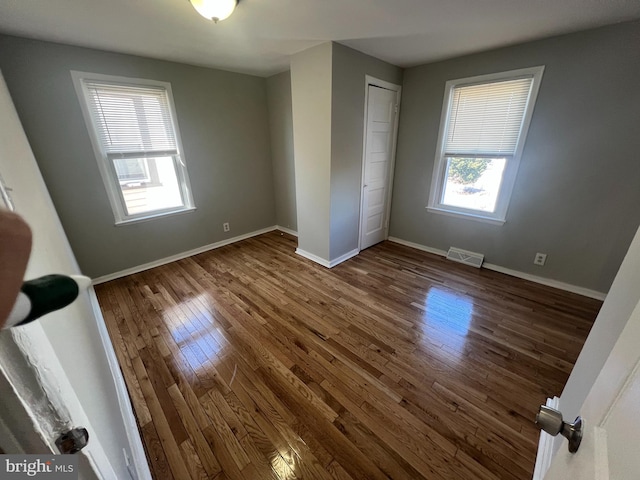 unfurnished bedroom featuring a closet, wood-type flooring, visible vents, and baseboards