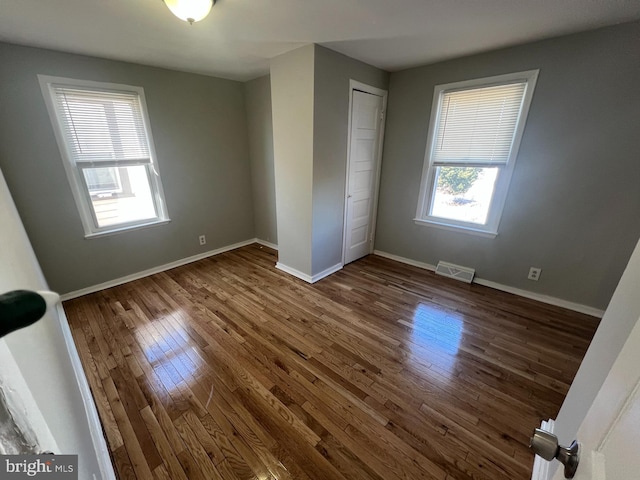 unfurnished bedroom with baseboards, wood-type flooring, visible vents, and a closet