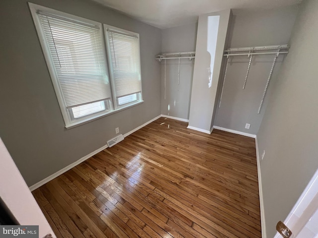 unfurnished bedroom with multiple closets, baseboards, visible vents, and hardwood / wood-style floors