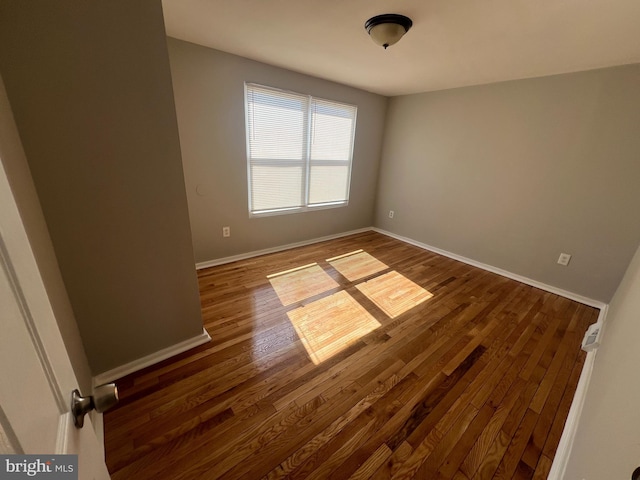 spare room with hardwood / wood-style flooring and baseboards