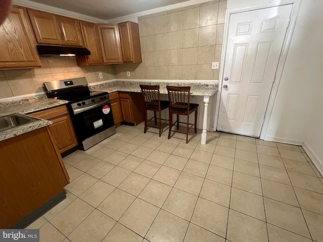 kitchen with electric stove, under cabinet range hood, decorative backsplash, and light tile patterned floors