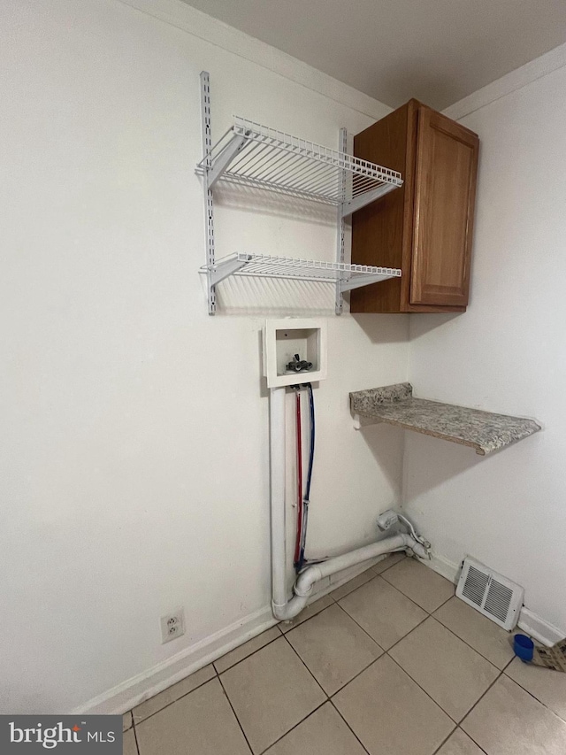 clothes washing area with cabinet space, light tile patterned floors, baseboards, visible vents, and washer hookup