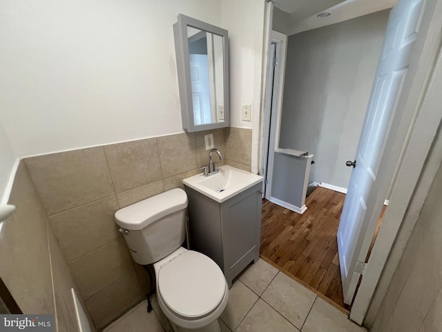 bathroom featuring toilet, tile patterned floors, tile walls, and vanity