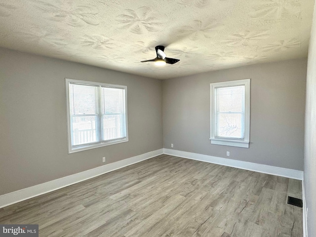 spare room with visible vents, baseboards, and wood finished floors