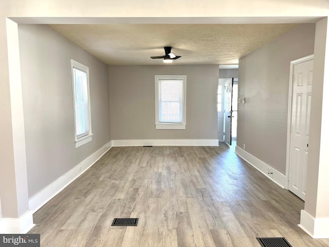 interior space with ceiling fan, a textured ceiling, baseboards, and wood finished floors