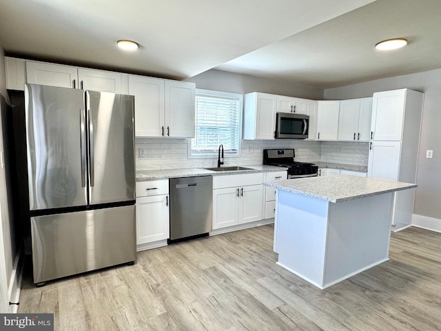 kitchen with appliances with stainless steel finishes, light wood-type flooring, a sink, and white cabinetry