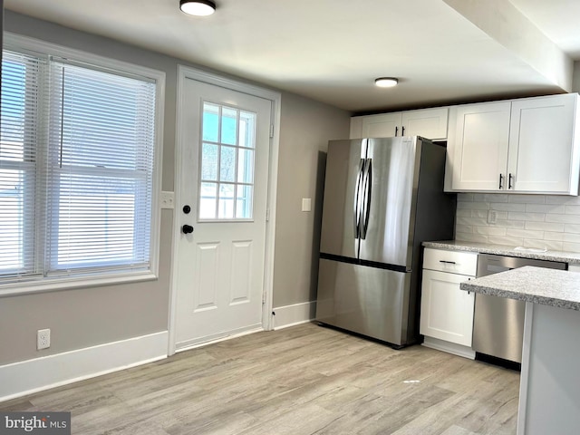 kitchen featuring white cabinetry, light wood-style flooring, appliances with stainless steel finishes, and backsplash