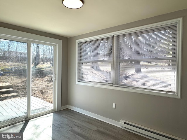 unfurnished dining area with baseboards, baseboard heating, and dark wood-type flooring