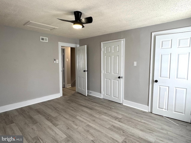 unfurnished bedroom featuring attic access, visible vents, baseboards, and wood finished floors